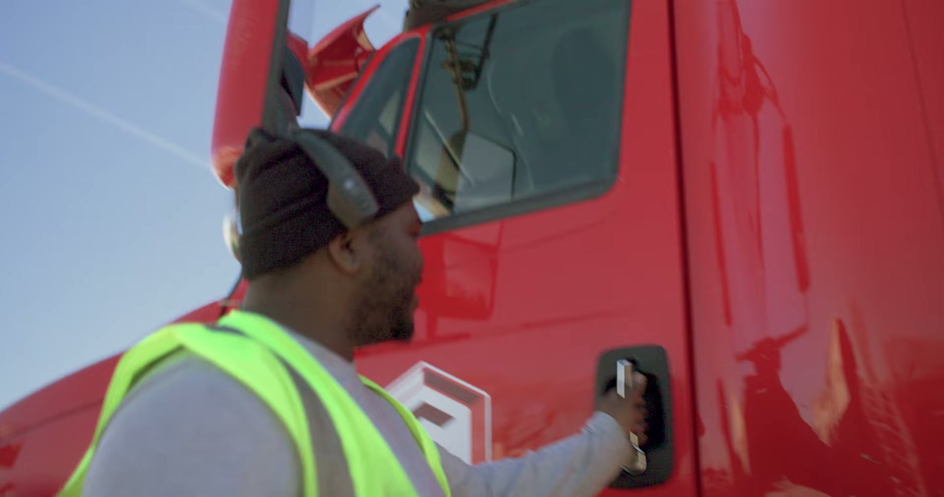 Carroll driver in a hi-vis vest stepping into the cab of a red Carroll tractor