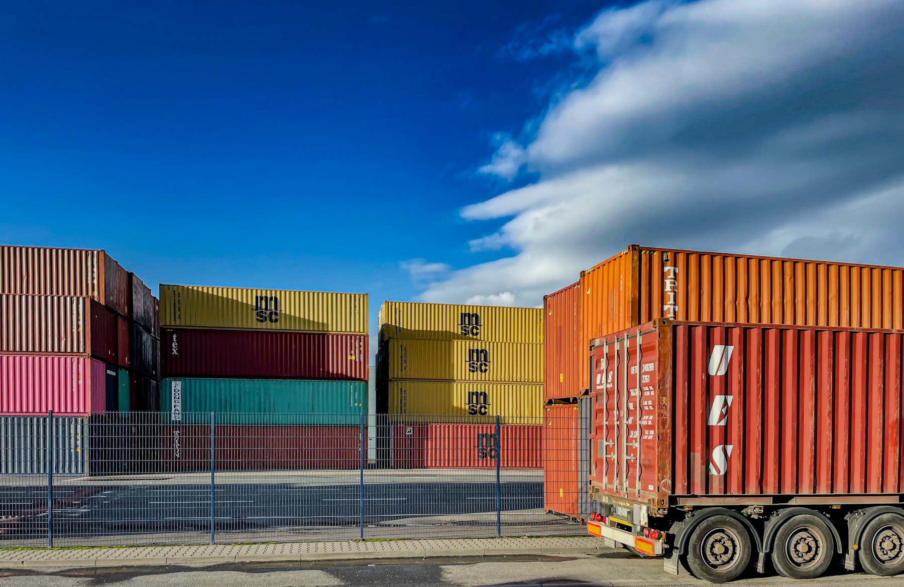 Container truck moving through a terminal with stacked shipping containers